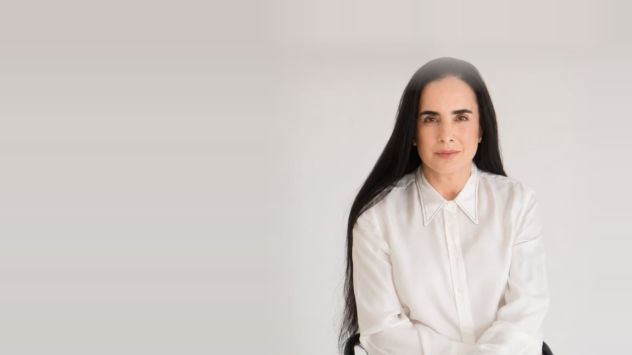 Isha Judd, retrato de estudio sentada en una silla, con camisa blanca